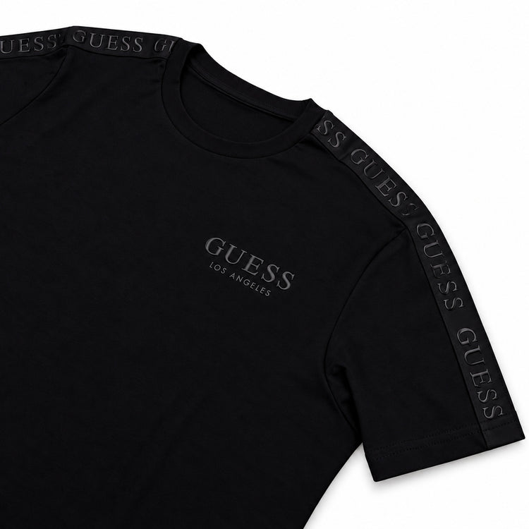 Detalle de logo y letras engomadas de polera Guess negra